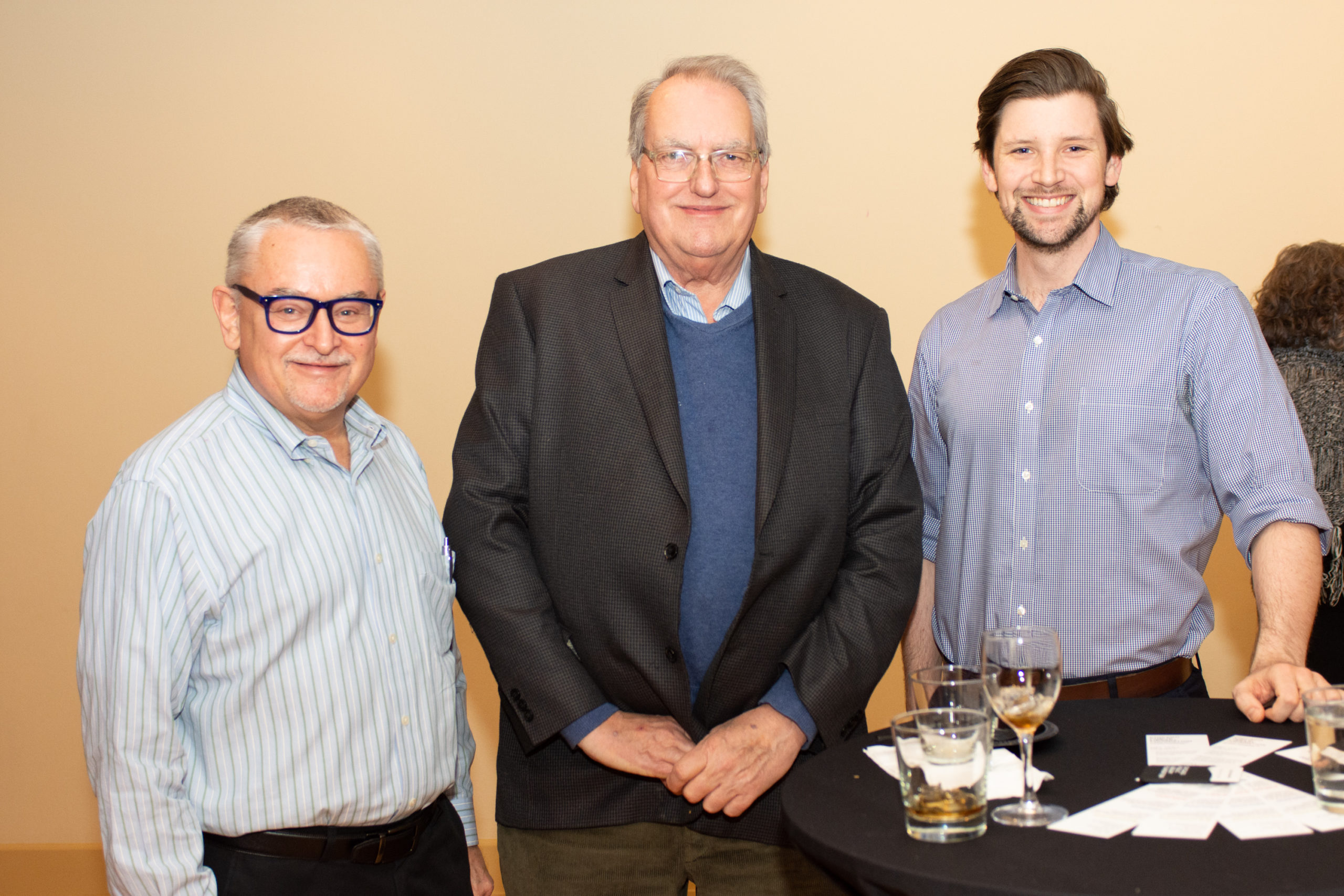 Three men standing next to a table.