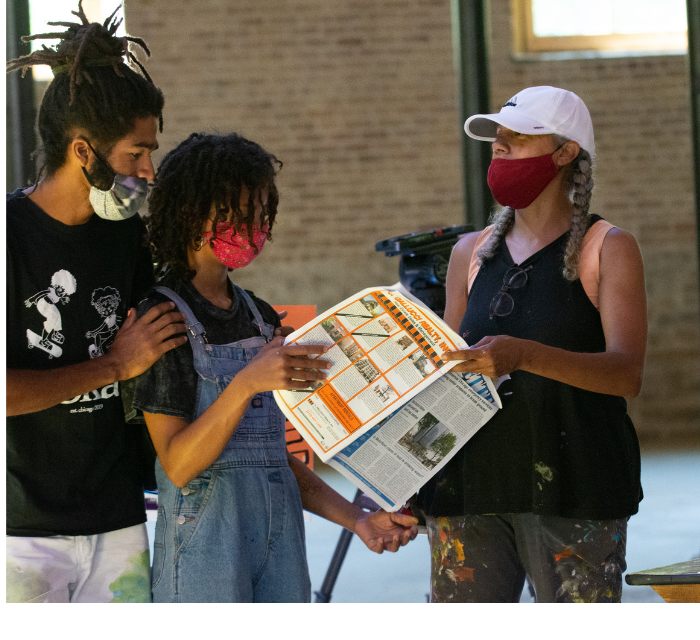 Three individuals are looking at a pamphlet.