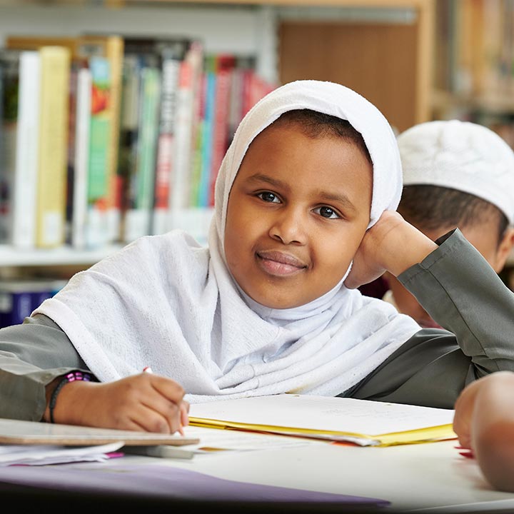 Girl looking up from her homework and smiling.