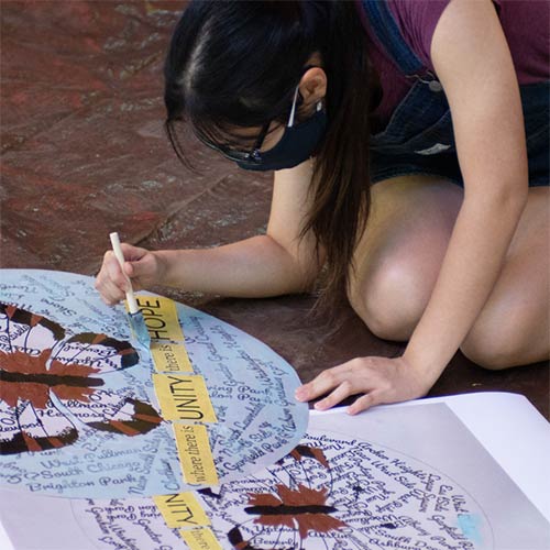 A girl painting a banner on the floor