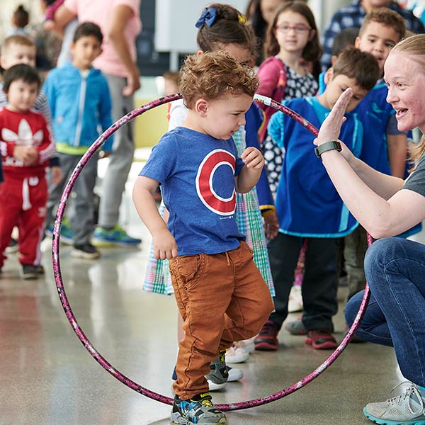 A kid getting a high five from a teacher for walking through her hula hoop